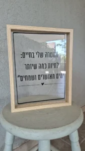 המסגרת עם הציטוט על שרפרף, והקיר נראה מבעד לפרספקס